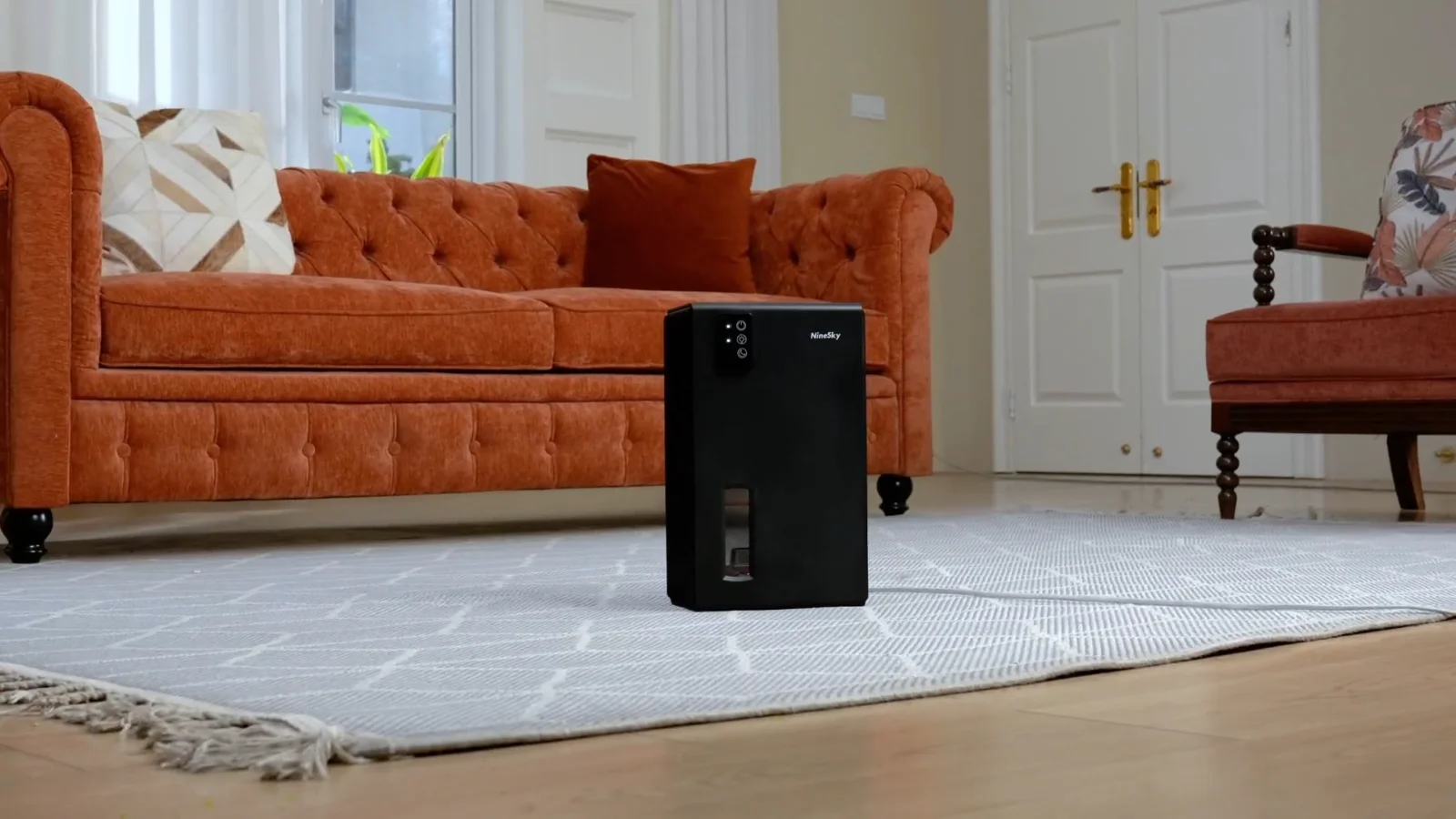 A black NineSky CT2 dehumidifier working on a living room rug
